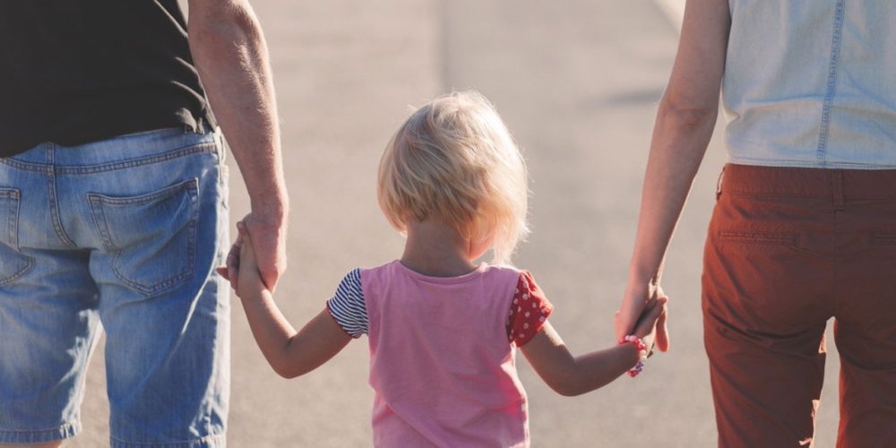 Child Holding Hands With Parents walking down the street