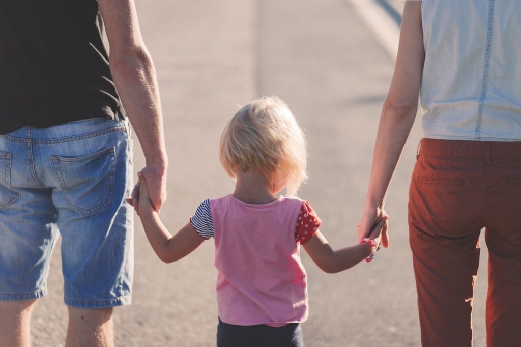 Child Holding Hands With Parents walking down the street